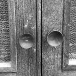 Schwarzweiß-Foto Detail einer Türe mit runden Türknäufen und Strukturverglasung